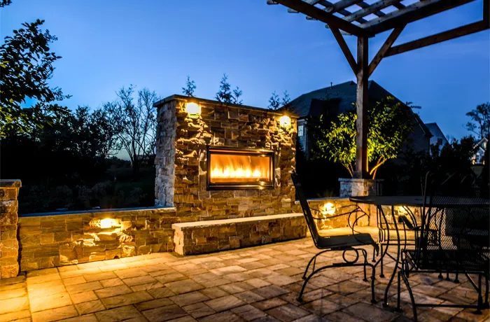 A stone fireplace under a cedar pergola in Brentwood