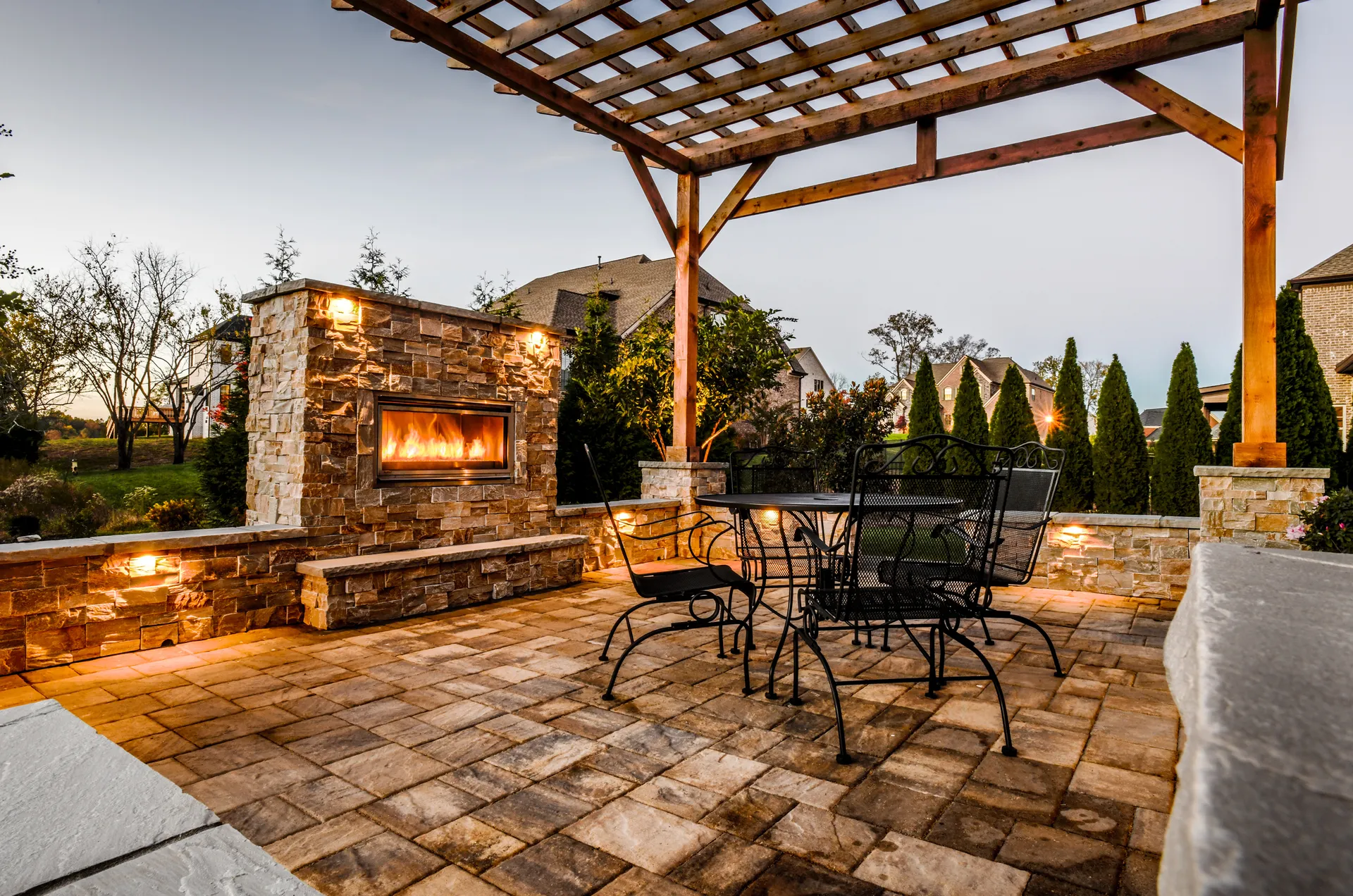 A stacked-stone fireplace and paver patio in Brentwood, lit at night
