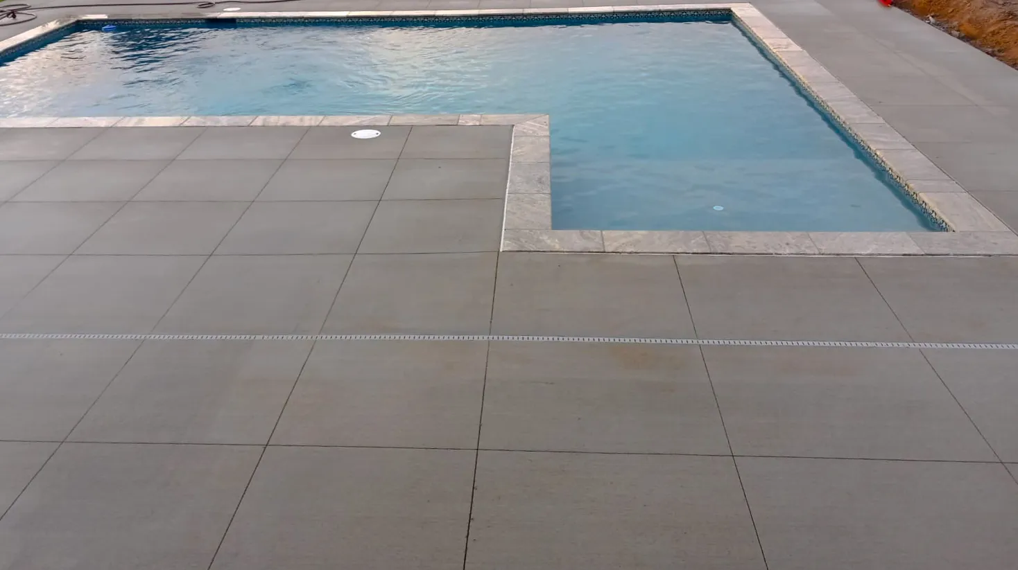 A concrete pool deck around a covered pool
