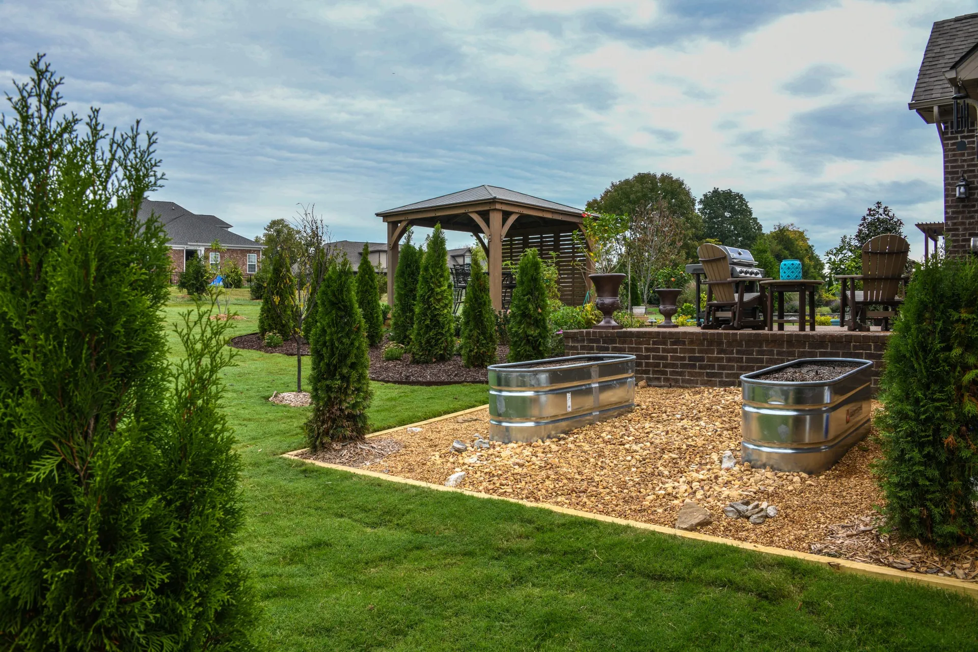 A container garden beside a row of arborvitae