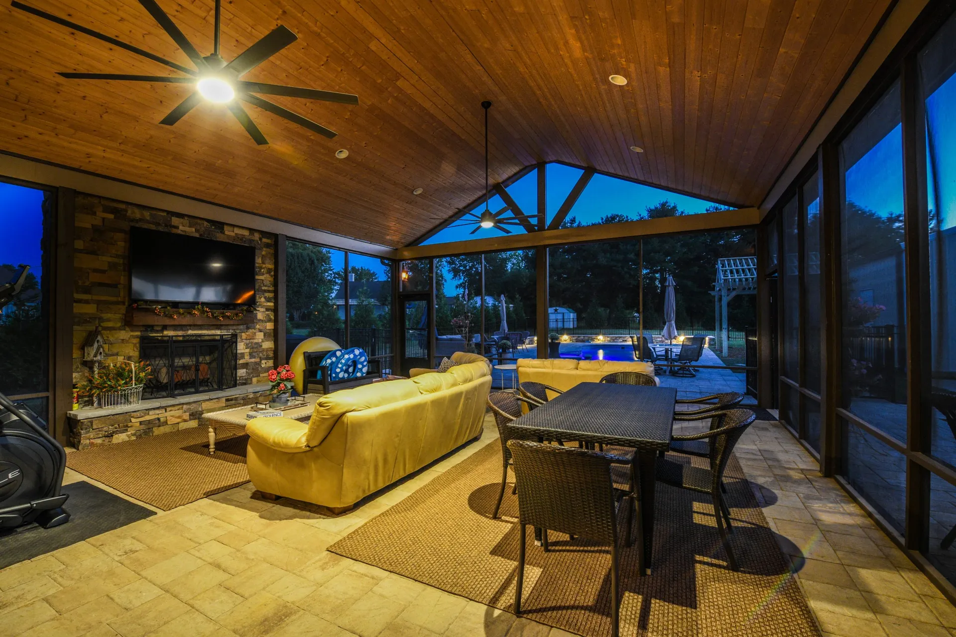 A screened porch with a stone fireplace, lit at night