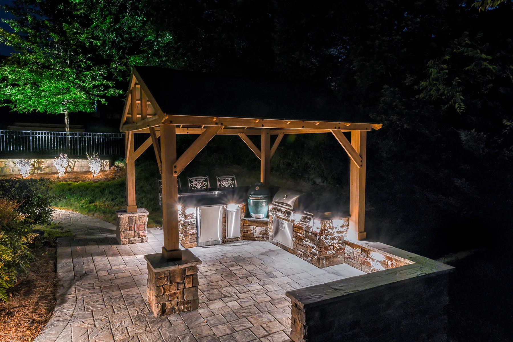 A timber pavilion with an outdoor kitchen, lit at night
