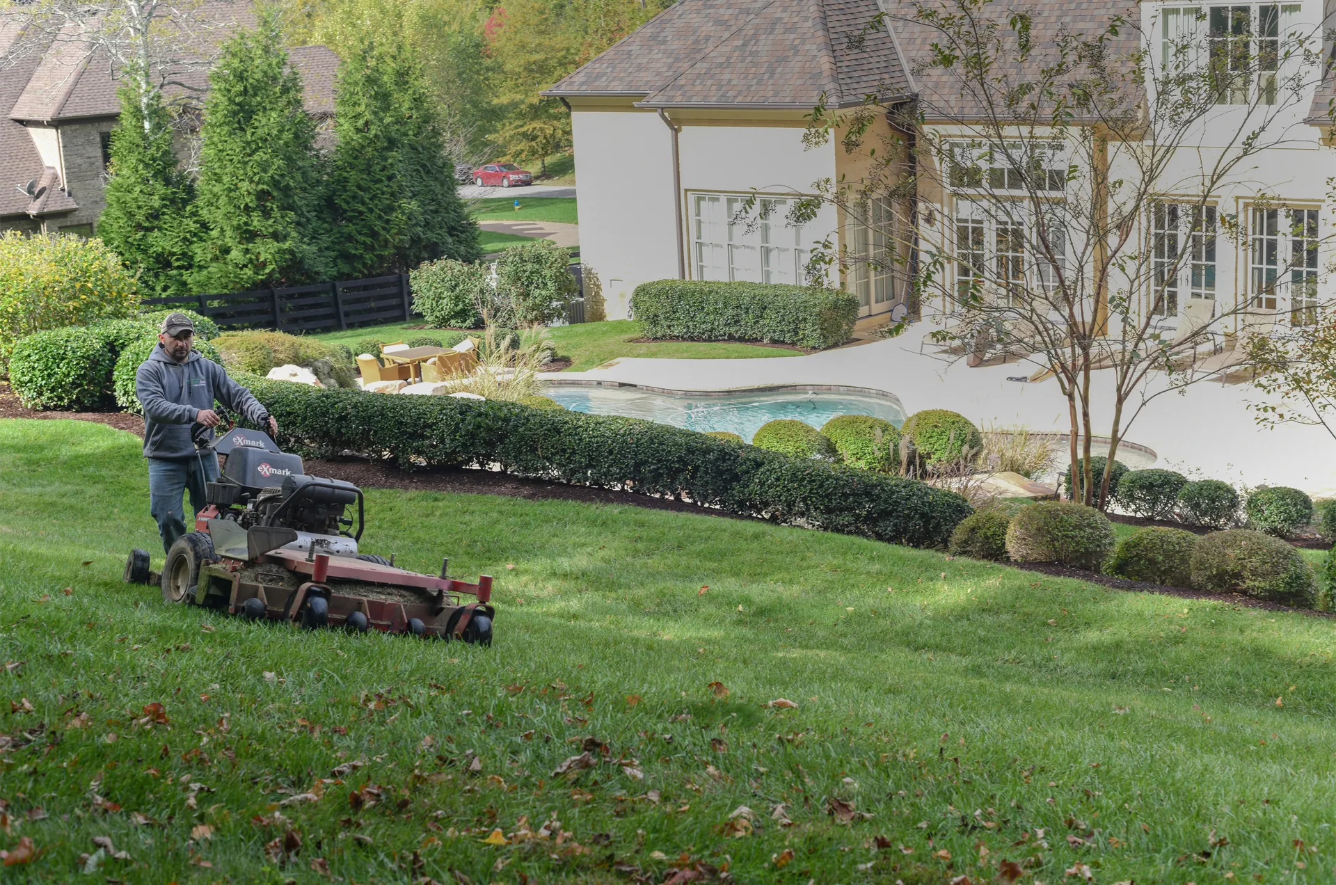 A Green Scene crewman on a zero-turn mower cutting a front lawn in Franklin